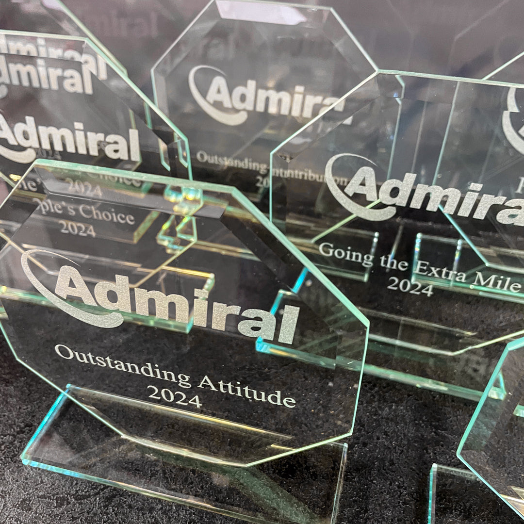 Glass awards with 'Admiral' branding on a dark surface