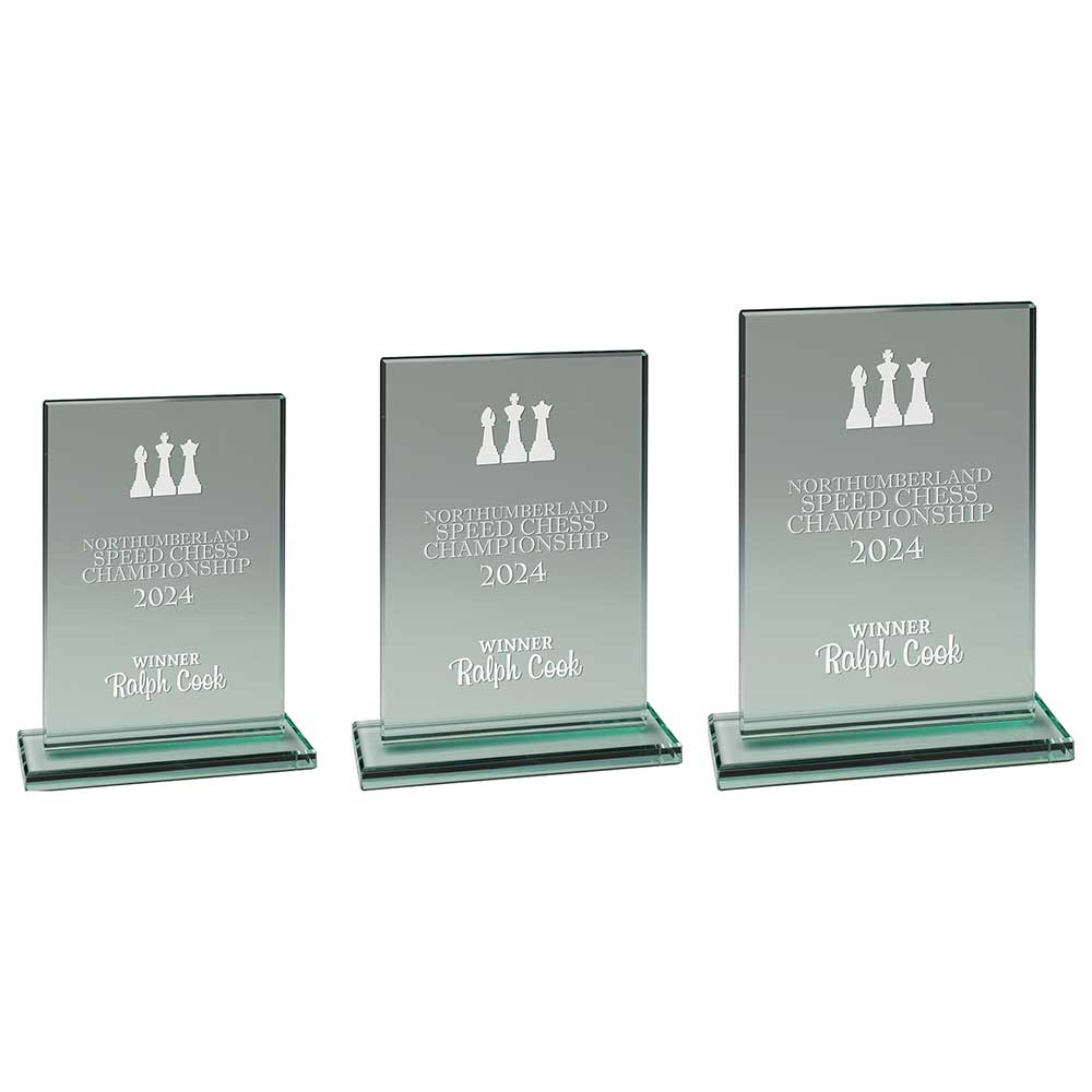 Three glass awards with engraved text and chess piece symbols on a white background