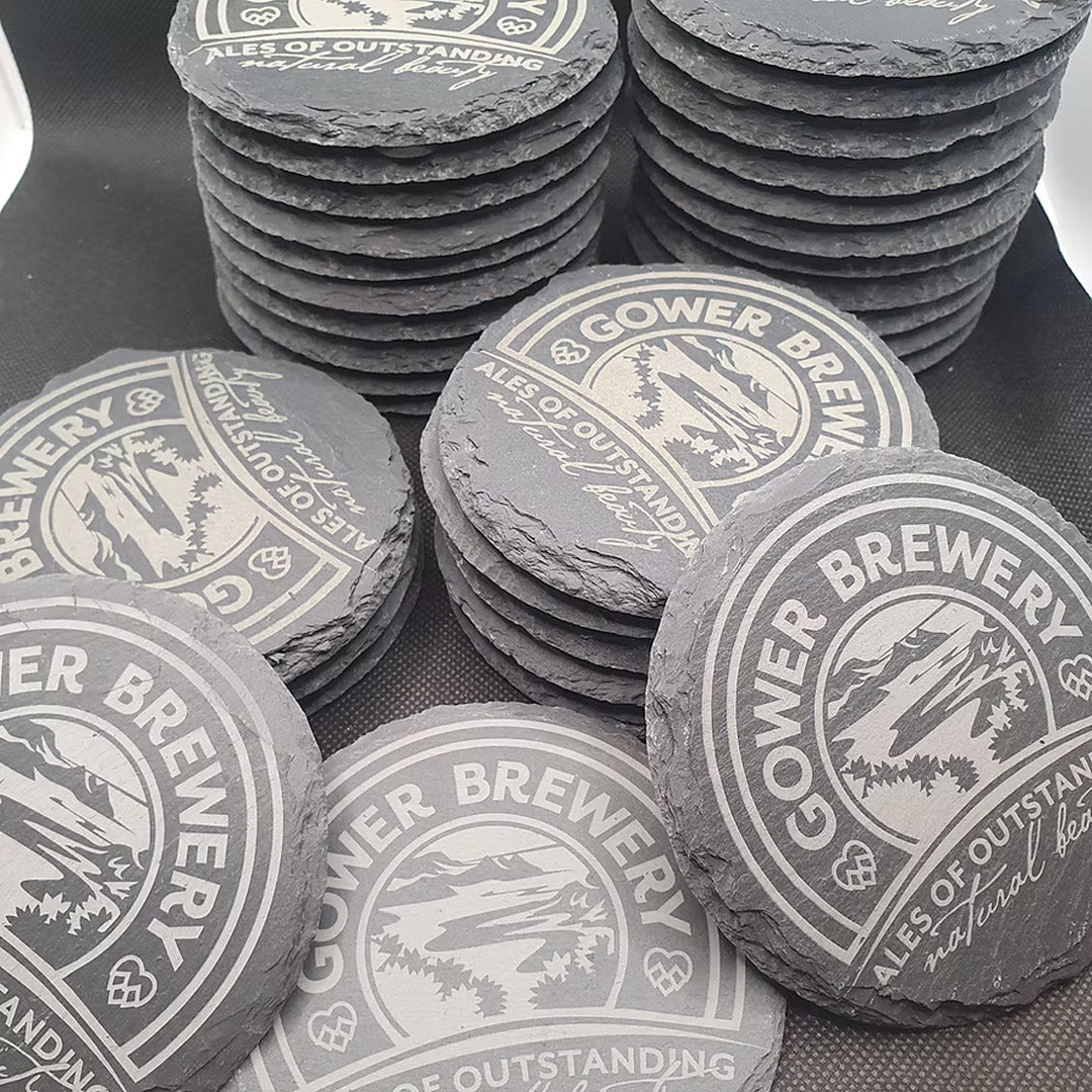 Stacks of Gower Brewery coasters on a dark surface