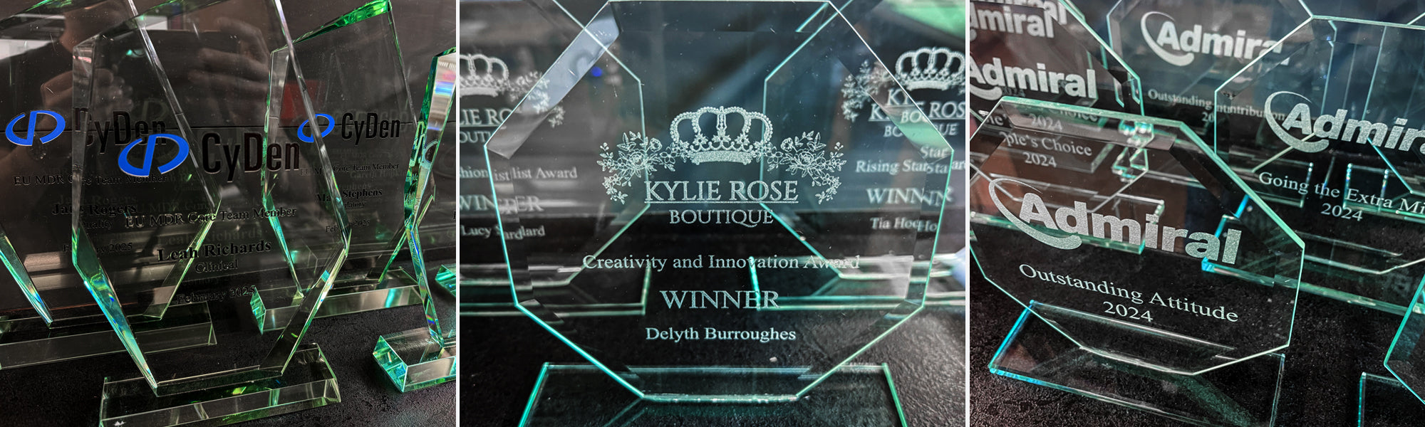 Collection of glass awards with branding on a dark background