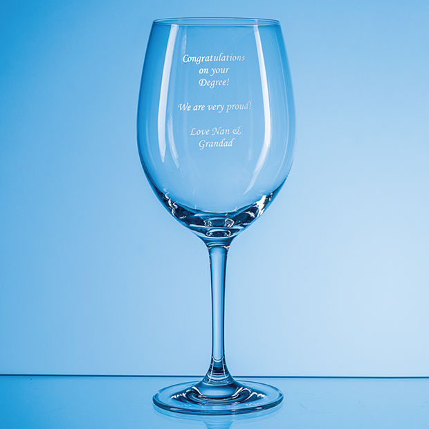 Clear wine glass with engraved text on a blue background