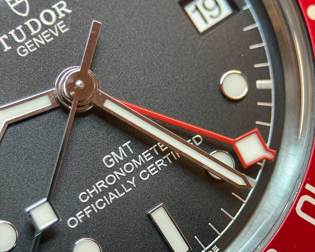 Close-up of a Tudor watch face with red hand and black dial