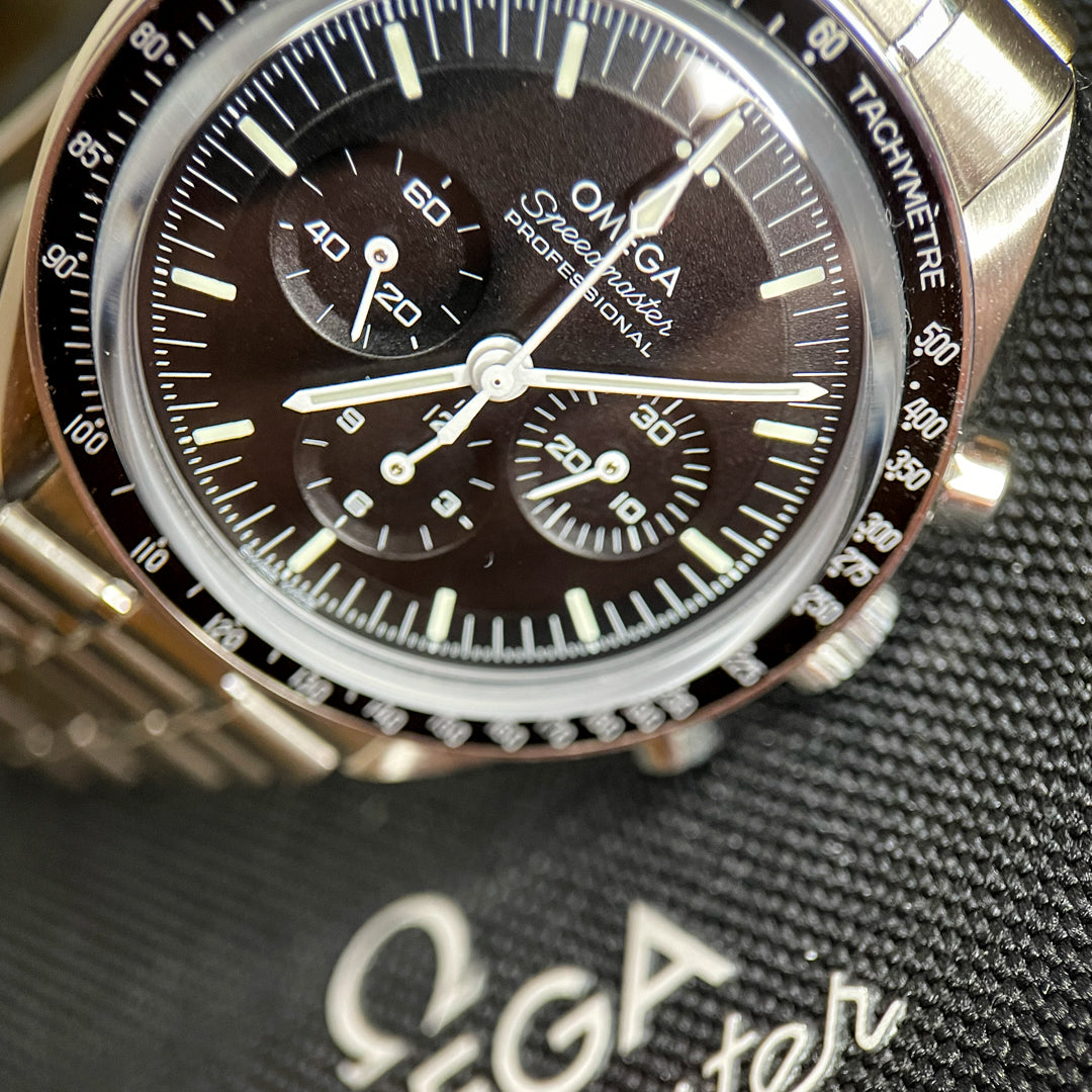 Close-up of a Omega Speedmaster watch with a brown dial on a textured surface.